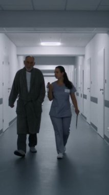 Hemşire ve yaşlı hasta tıp merkezi koridorunda yürür ve test sonuçlarını tartışırlar. Sağlık uzmanı hastane koridorunda telefonla konuşuyor. Klinikte çok ırklı tıbbi personel çalışıyor. Dikey çekim