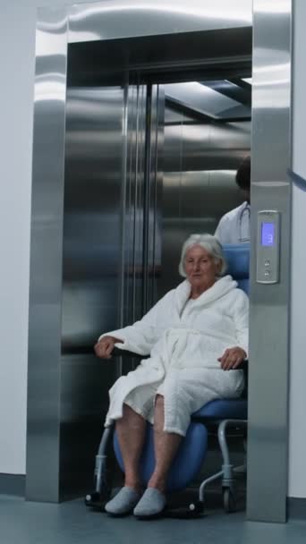 医生把病人从电梯转移到轮椅上 医生会带老年妇女接受手术或在诊所走廊上行走手术室 医护人员和病人在医院走廊 — 图库视频影像