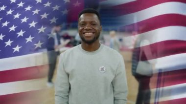 Rozetli Afro-Amerikan vatandaşı gülümseyip kameraya bakıyor. Amerikan bayrağını sallamanın 3 boyutlu görsel efekti. Reklam, Birleşik Devletler 'de başkanlık seçimi için oylama çağrısı yapıyor. Vatanseverlik.