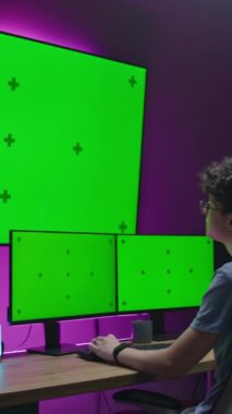 Genç editör, 3D tasarımcı ev stüdyosunda çalışıyor, film düzenliyor, video oyunu geliştiriyor, 3D animasyon yaratıyor. Ergen çoklu monitörlü bilgisayar ve büyük dijital ekranda kromakeyle oturuyor.