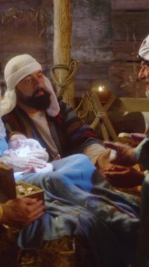 Magi, bebek İsa ile birlikte Meryem ve Yusuf 'un etrafında toplandı ve Noel günü Beytüllahim' deki karanlık ahırda Tanrı 'nın oğlunu övdü. Dikey çekim.