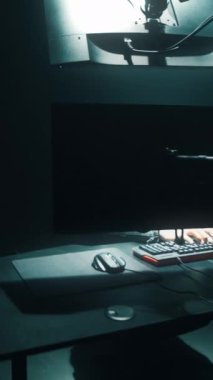 Maskeli bir hacker 'ın yeraltı sığınağından şirket veri sunucularına girdiği fikri karanlık bir atmosferi ve birden fazla ekranı var. Dikey çekim.