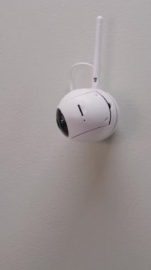 Woman completes installation of security camera. Woman sets up angle of CCTV camera at home using mobile phone and professional application. Monitoring and tracking system, safety and privacy concept.