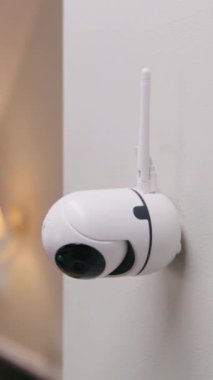 Modern apartmanın duvarına yerleştirilmiş güvenlik kamerasının yakın çekim görüntüsü. Mikrofon ve hareket sensörlü CCTV kamerası. İzleme sistemi, gözetleme ve kişisel mahremiyet kavramı. Dikey çekim.