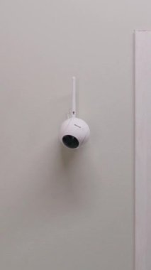 Modern apartmanın duvarına yerleştirilmiş güvenlik kamerasının dikey görüntüsü. Mikrofon ve yeşil göstergeli CCTV kamerası. İzleme sistemi, izleme, güvenlik ve kişisel mahremiyet kavramı