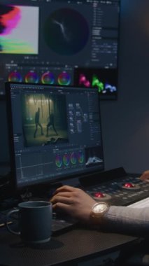 Afrikalı Amerikalı film yapımcısı modern stüdyoda bilgisayardan renk değerlendirmesi yapıyor. Duvarında RGB renk düzeltme çubuğu olan büyük ekran. Ekranda gösterilen aksiyon filmi görüntüleri. Renkçi ekipman.