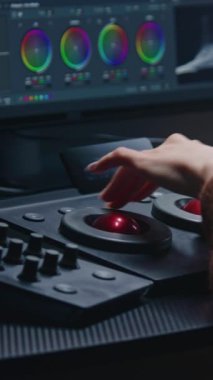 Stüdyoda çalışan kadın editör, dijital renk derecelendirme kontrol paneli kullanıyor. Renkçi bilgisayarda görüntü renk düzeltmesi yapıyor. PC monitöründeki RGB grafikleri, renk çarkları ve seviyeleri ile program arayüzü.