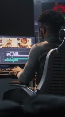 Afrikalı Amerikalı renklendirici video düzenleme yazılımında renk derecelendirme yapıyor. Uzay yolculuğu film görüntülerine ve RGB renk düzeltme çubuğuna sahip birden fazla monitör. Modern stüdyoda post prodüksiyon.