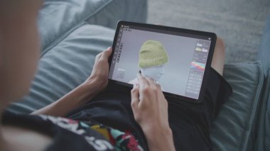 Elinde tablet olan ve dijital stili olan çocuk evde oturup 3 boyutlu modeller yaratıyor. Odaklanmış genç, 3D modelleme programı kullanarak oyun karakteri için kıyafet çiziyor. Geliştirme ve oyun tasarımı konsepti. Kapat..