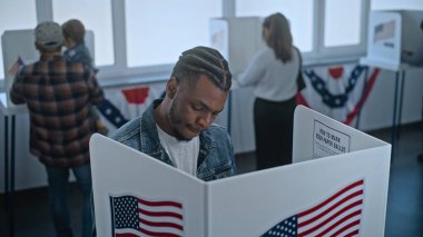 Afro-Amerikalı adam oy kullanma merkezindeki kabine oy vermeye geliyor. Birleşik Devletler 'de Ulusal Seçim Günü. ABD başkan adaylarının siyasi ırkları. Vatanseverlik ve vatandaşlık görevi kavramı.