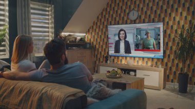 Beyaz çift büyük bir televizyon programında flaş haber izliyor ve evdeki koltukta otururken ABD başkanlık seçimlerini tartışıyor. TV 'de kadın haber spikeriyle televizyon haberleri yayınlanıyor