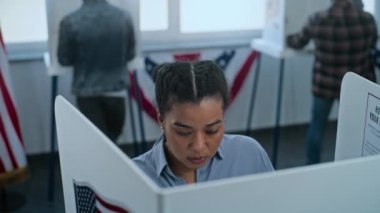Afro-Amerikalı kadın oy kullanma merkezindeki oy verme kabininde duruyor. Birleşik Devletler 'de Ulusal Seçim Günü. ABD başkan adaylarının siyasi ırkları. Vatandaşlık görevi kavramı. Dolly vurdu..