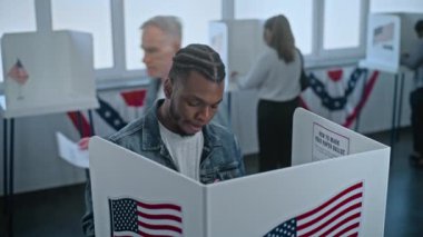 Afro-Amerikalı adam oy kullanma merkezindeki kabine oy vermeye geliyor. Birleşik Devletler 'de Ulusal Seçim Günü. ABD başkan adaylarının siyasi ırkları. Vatanseverlik ve vatandaşlık görevi kavramı.