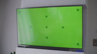 Sıcak, modern oturma odasının duvarında renkli anahtar yeşil ekranlı büyük bir televizyon. Model şablonlu arka plan ve ekranda izole edilmiş krom anahtar. Işık odasında düz ekran TV monitörü. Kapat..