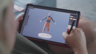 Beyaz kadın tablet bilgisayar ve dijital kalem kullanarak 3D modelleme uygulamasında model oluşturur. Yetişkin bir kadın, evdeki kanepede uzanarak kendi işini yapıyor. Yaşam tarzı ve uzaktan çalışma. Kapat..