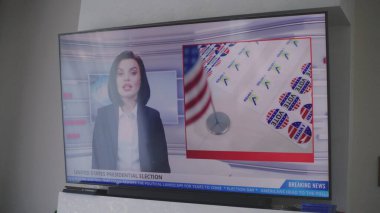 Oturma odasındaki duvarda, Amerika Birleşik Devletleri 'ndeki seçimlerle ilgili televizyon haberleri olan büyük bir televizyon var. ABD 'de ulusal seçim günü. Televizyon canlı yayında. Vatandaşlık görevi ve vatanseverlik. Kapat..