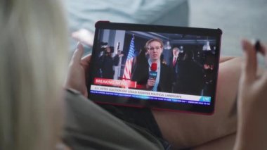 Beyaz kadının ABD Seçim Günü ile ilgili son dakika haberlerini izlerken kanepede otururken tablet bilgisayar kullanmasını kapatın. Tablet ekranında görüntülenen kadın gazetecinin haber kaydı.