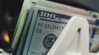 Para sayma makinesi döviz, bütçe hesaplaması ya da yatırım için 100 dolarlık banknotları sayar. Otomatik fatura sayacı. 100 dolarlık banknotlar. Finans ve bankacılık kavramı. Kapat..