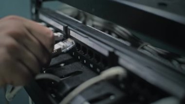 Erkek ağ yöneticisi sunucu odasında internet ekipmanlarıyla çalışan sunucu rafına kablolar yerleştirir. LAN 'in bakımı, bilgisayar ağları ve web sunucuları. Veri depolama merkezi. Kapat..