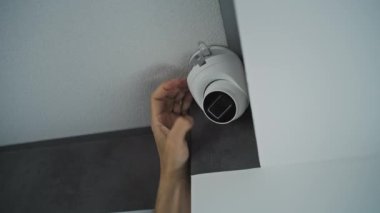 Profesyonel erkek kurucu ofis odasının tavanına kamera vidalıyor ve açıyı ayarlıyor. İzleme ve izleme. Video izleme, güvenlik sistemi ve mahremiyet.