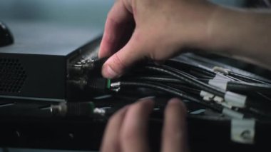 Close up of male network administrator inserting cables into server rack setting up internet equipment in server room. Maintenance of LAN, computer networks and web servers. Data storage center.