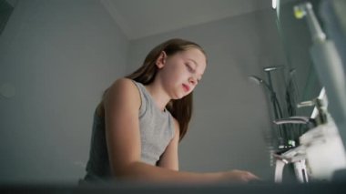 Sevimli genç kız banyoya gelir, yüzünü soğuk suyla yıkar ve aynaya bakar. Yumuşak yüzlü güzel bir kız lavabonun yanında durur, yüzünü havluyla siler. Banyo sabahı rutini.