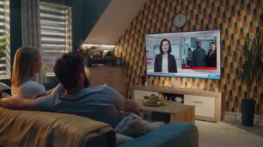 Beyaz çift büyük bir televizyon programında flaş haber izliyor ve evdeki koltukta otururken ABD başkanlık seçimlerini tartışıyor. TV 'de kadın haber spikeriyle televizyon haberleri yayınlanıyor