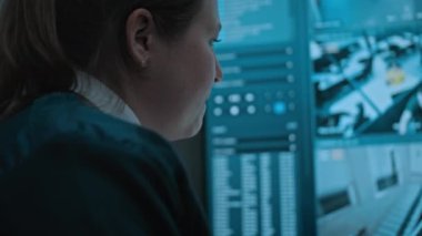 Çok ırklı gözetleme operatörleri izleme merkezindeki güvenlik kameralarını kontrol ediyor. Kadın güvenlik görevlisi Afrikalı Amerikalı erkek meslektaşıyla konuşuyor, kapalı devre kamera görüntülü tablet bilgisayar kullanıyor..