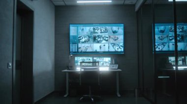 Bilgisayar monitörleri, tablet ekran ve ofisteki CCTV kameralarının güvenlik kamerası görüntülerini gösteren büyük dijital ekran. Loş modern izleme merkezinde güvenlik işçisi veya operatör için çalışma yeri.