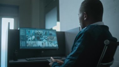 Afrika kökenli Amerikalı erkek güvenlik görevlisi ofisteki iş yerinde cep telefonu kullanıyor. Güvenlik kameralarından gerçek zamanlı görüntülü bilgisayar monitörü. CCTV sistemi ve sosyal güvenlik.