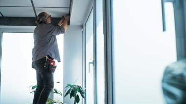 Üniformalı profesyonel erkek teknisyen ofis odasındaki güvenlik kameralarını aletlerle kuruyor ve vidalıyor. İzleme ve izleme sistemi. Gözetim sistemi, CCTV ve gizlilik kavramı.