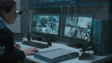 Çoklu monitörler ve güvenlik kamerası görüntülerini gösteren büyük dijital ekran. Kadın sevkiyatı ya da CCTV operatörü, güvenlik kameraları ve telsizle konuşan izleme merkezindeki bilgisayarda çalışıyor..