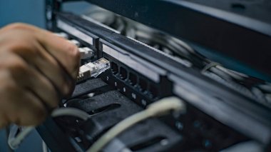 Erkek ağ yöneticisi sunucu odasında internet ekipmanlarıyla çalışan sunucu rafına kablolar yerleştirir. LAN 'in bakımı, bilgisayar ağları ve web sunucuları. Veri depolama merkezi. Kapat..