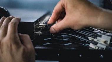 Sunucu odasına internet ekipmanları kuran erkek ağ yöneticisinin sunucu rafına kablo yerleştirmesini kapatın. LAN 'in bakımı, bilgisayar ağları ve web sunucuları. Veri depolama merkezi.