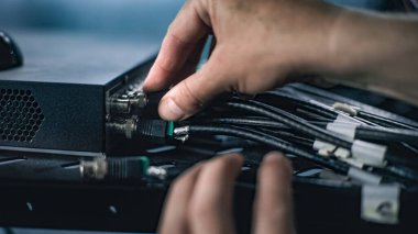 Sunucu odasına internet ekipmanları kuran erkek ağ yöneticisinin sunucu rafına kablo yerleştirmesini kapatın. LAN 'in bakımı, bilgisayar ağları ve web sunucuları. Veri depolama merkezi.