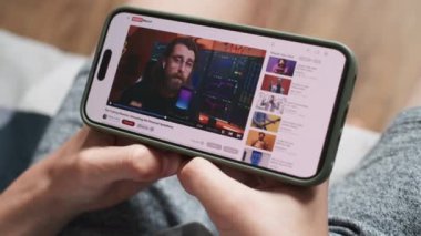 Akıllı telefon ekranında sergilenen hisse senetleriyle ilgili blog içerikli video paylaşım platformu. Yatırım ya da kripto para hakkında videolar izleyen gençlerin yakın plan çekimleri..