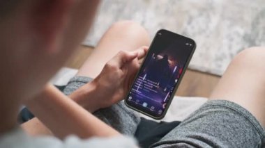 Kafkasyalı genç evdeki kanepede oturur, internette cep telefonu kullanarak sörf yapar, boş zamanlarını geçirir. Sosyal medya, akıllı telefon ekranında dans eden genç kızın kısa videosuyla besleniyor. Kapat..