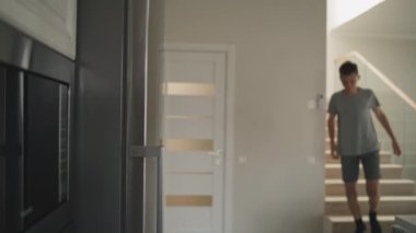 Beyaz tenli genç şık ve modern bir evde merdivenlerden iniyor, buzdolabını açıyor, içki ve atıştırmalık alıyor, sonra odasına çıkıyor. Genç çocuk evde vakit geçiriyor. Yaşam tarzı kavramı.