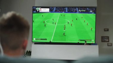 ZAPORIZHYA, UKRAINE - 7 Haziran 2024: TV ekranında gösterilen çevrimiçi futbol oyunu. Oturma odasında kanepede oturup boş zamanlarını geçirirken beyaz tenli bir çocuğun konsol oynaması..