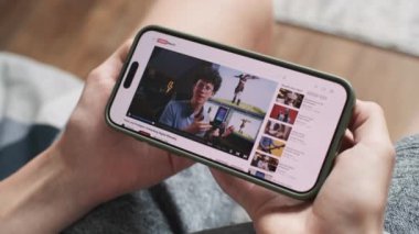 Smartphone ekranında oyun geliştirme hakkında blog içerikli video sunuculuğu web sitesi var. Üç boyutlu modellik ve animasyonla ilgili özel ders videolarını kanepede otururken yakın çekim yap..