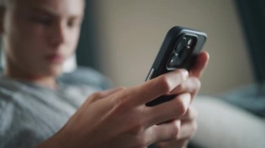 Kanepede otururken cep telefonu kullanarak mesajlaşma uygulamasında arkadaşlarıyla yazışan ve sohbet eden ergen çocuklara yakın durun. Kafkasyalı ergen dinleniyor ve hafta sonunu evde geçiriyor. Yaşam tarzı kavramı.