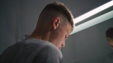 Beyaz çocuk banyoda dikiliyor ve aynadaki yansımasına bakıyor. Ergen, lavabonun yanında duruyor ve yatmadan önce banyoyu rutin hale getiriyor. Yaşam tarzı kavramı. Arkadan bak. Kapat..