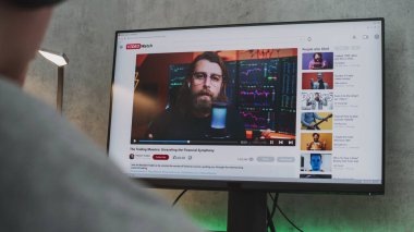 PC monitörü, video paylaşım platformunun hisse senedi ticaretiyle ilgili blog içeriğini gösteriyor. Kulaklıklı genç çocuk evdeki kişisel bilgisayarda yatırım ve kripto para hakkında eğitici videolar izliyor..