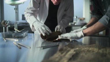 Bilim adamları soyu tükenmiş insan medeniyetinin kültürel mirasını araştırıyorlar. Eldivenli iki arkeolog, antik Mısır papirüsünü dikkatlice arkeoloji laboratuarında masaya yatırıp konuşuyorlar. Arkeoloji.