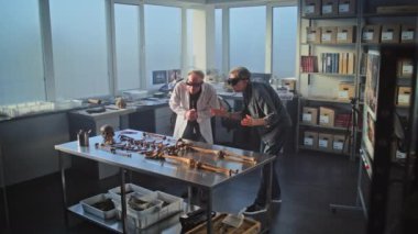 Sanal gerçeklik kulaklığı takan iki arkeolog antik soyu tükenmiş insan iskeletinin kalıntılarını inceliyor. Bilim insanları modern arkeoloji laboratuvarında çalışırken tarihsel ve bilimsel araştırmalar yapıyorlar..