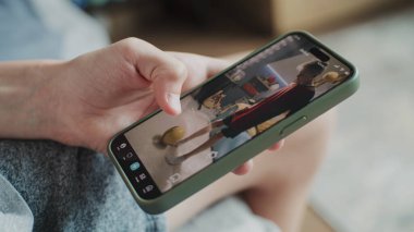 Telefon ekranında görüntülenen çeşitli video içerikli akıllı telefon uygulaması. Kanepede otururken cep telefonunu kullanarak sosyal medyanın kısa videolarla beslenmesini seyreden gençleri kapatın.