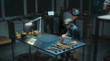 Geceleyin arkeoloji laboratuvarı: AR 'daki olgun arkeolog veya bilim adamı, sanal gerçeklik ve tablet bilgisayar kullanarak antik insan kalıntıları üzerinde tarihi araştırmalar yürütüyor. Yüksek açı