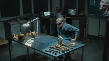 Geceleyin arkeoloji laboratuvarı: AR 'daki olgun arkeolog veya bilim adamı, sanal gerçeklik ve tablet bilgisayar kullanarak antik insan kalıntıları üzerinde tarihi araştırmalar yürütüyor. Yüksek açı