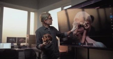 Erkek ve kadın bilim adamları veya arkeologlar konuşurlar, fosil kafatasını incelerler ve ileri arkeoloji laboratuvarında bilimsel araştırmalar yaparlar. Büyük ekranda eski insan kafası anatomisinin 3 boyutlu modeli gösteriliyor..