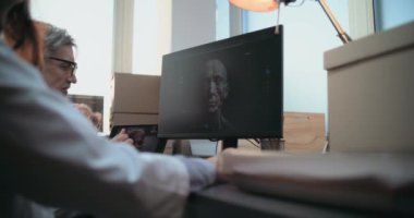 İki farklı bilim adamı bilgisayar ekranlarında ve tablet ekranlarda gösterilen insan kafası anatomisinin 3 boyutlu modelini tartışıyor, bilimsel araştırmalar yapıyorlar. Arkeologlar veya paleontologlar arkeoloji laboratuvarında çalışırlar.